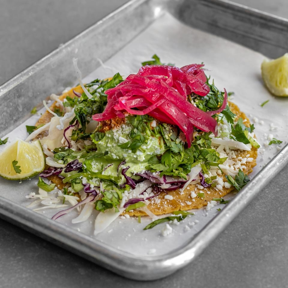 Taco with cabbage, pickled red onions, crumbled cheese and lime.
