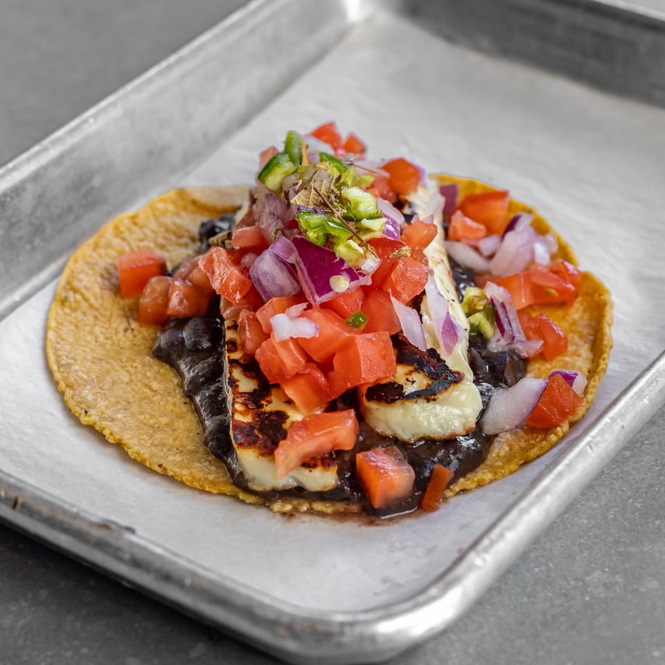 Taco with grilled cheese, black beans, tomatoes and red onion.