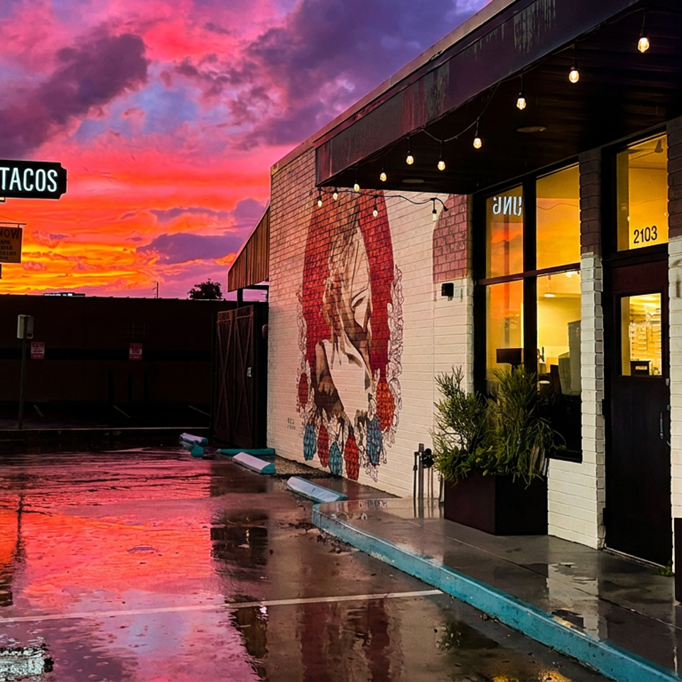 Hunger Street Tacos restaurant at sunset, with a vibrant sky reflecting on wet pavement.