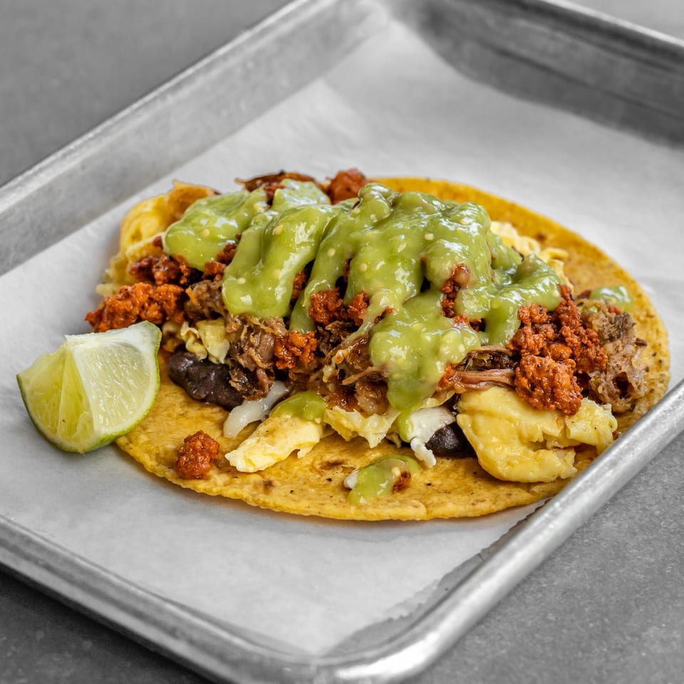 Corn tortilla topped with egg, chorizo, beans and green salsa.